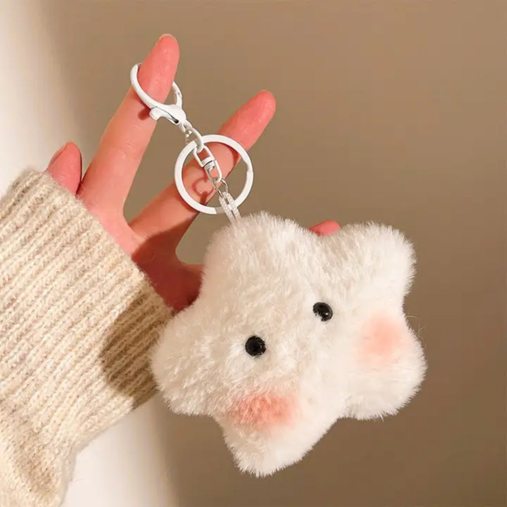 Cream star plush keychain with black eyes and pink cheeks, held by its silver clasp and keyring.